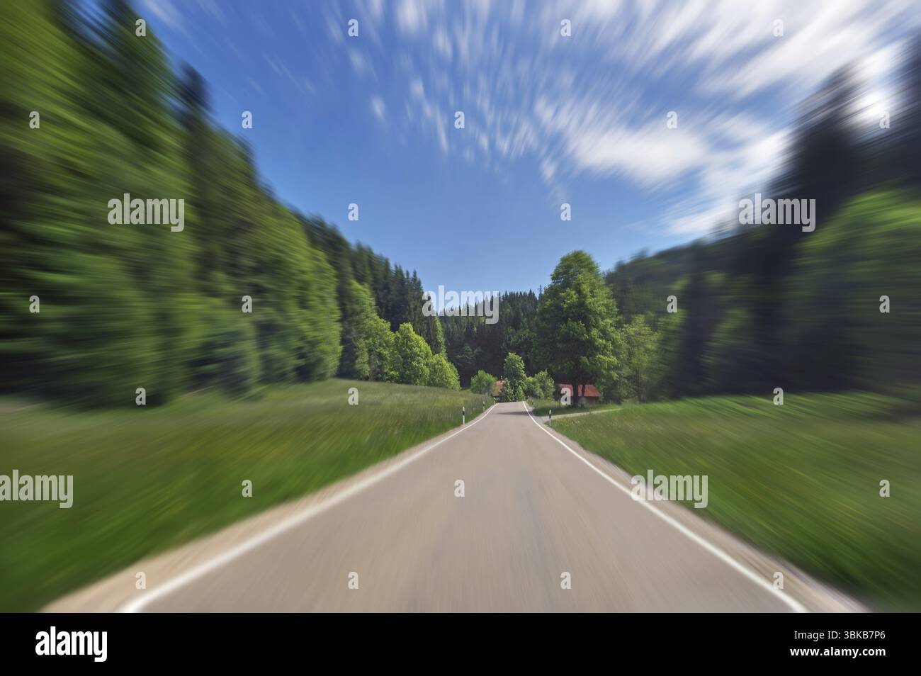 Effetto zoom, nuvole bianche, prati primaverili, strada di campagna e foresta mista nei pressi di Unterkuernach-Wiggensbach, Allgaeu, Svevia, Baviera, Germania, Europa Foto Stock