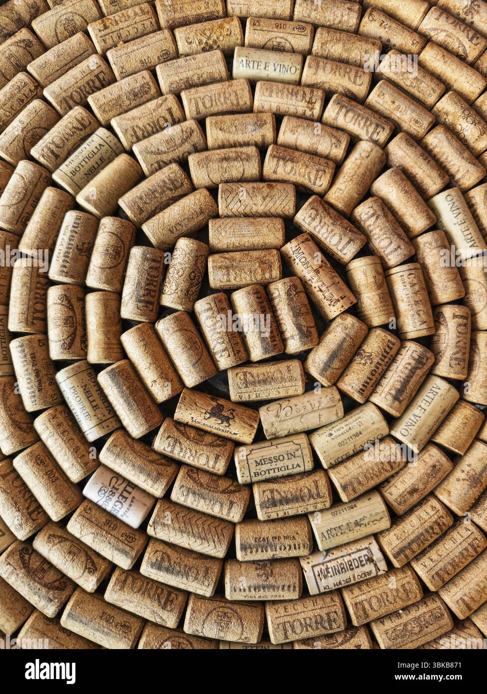 Un gran numero di sugheri di vino stesi insieme in un modello a spirale. I sugheri provengono da diverse cantine e recano varie impronte, loghi e lettere Foto Stock