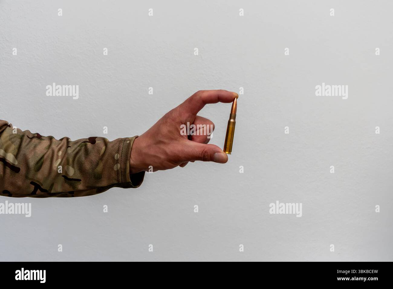 Una sola cartuccia nella mano di un soldato. Immagine minimalista che trasmette il tema delle armi, della guerra e dello scatto decisivo Foto Stock