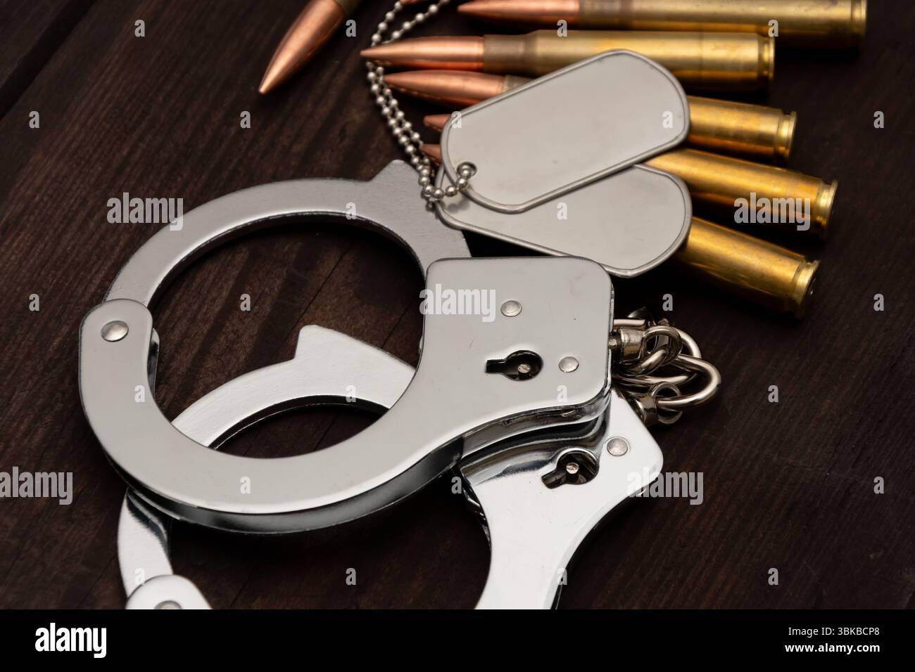 Un primo piano di polsini lucidi, due stemmi militari e diverse cartucce. Gli oggetti sono adagiati su uno sfondo di legno invecchiato Foto Stock