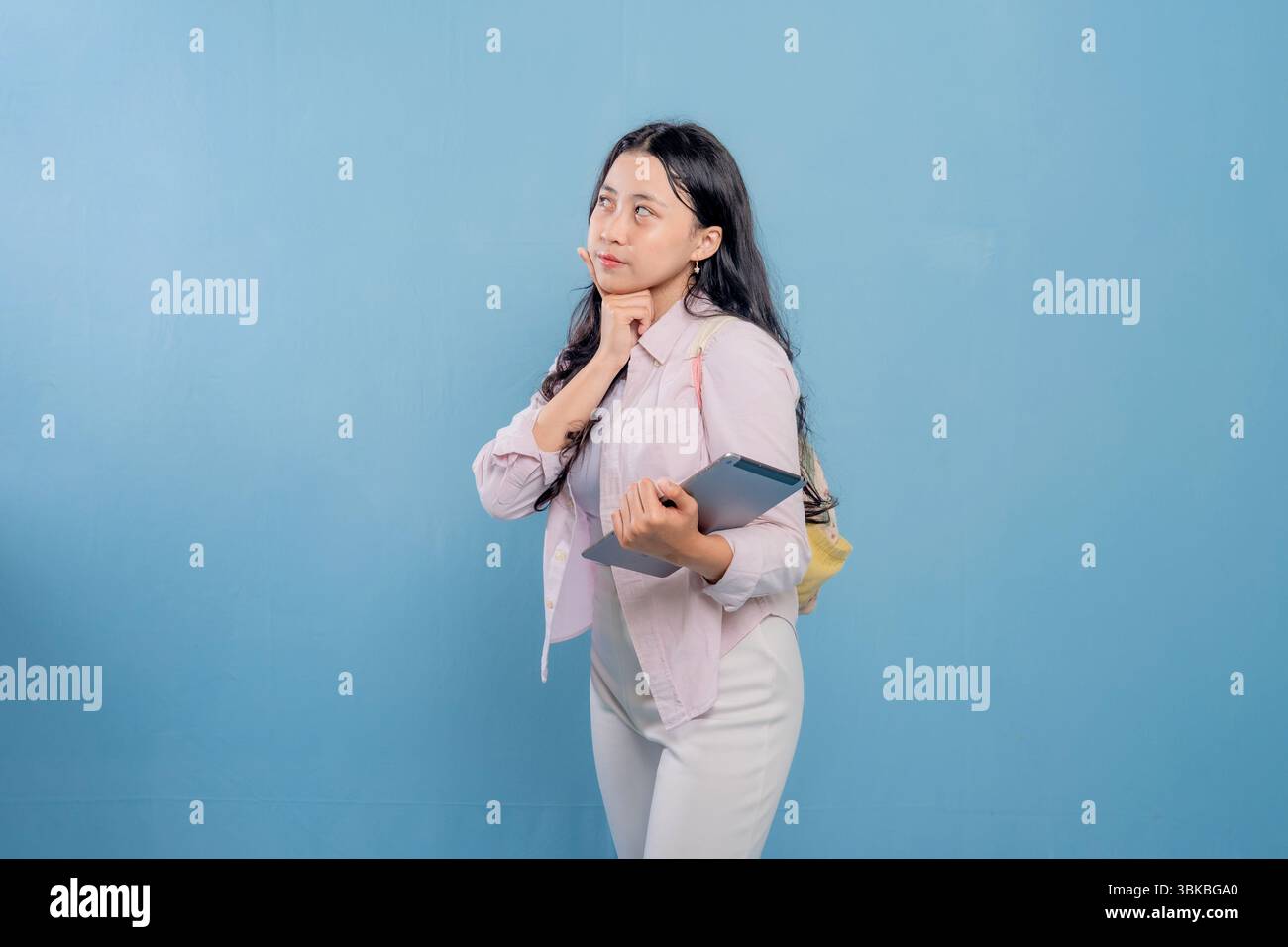 Una donna tiene in mano un tablet e guarda il soffitto. Lei è profondamente pensata Foto Stock