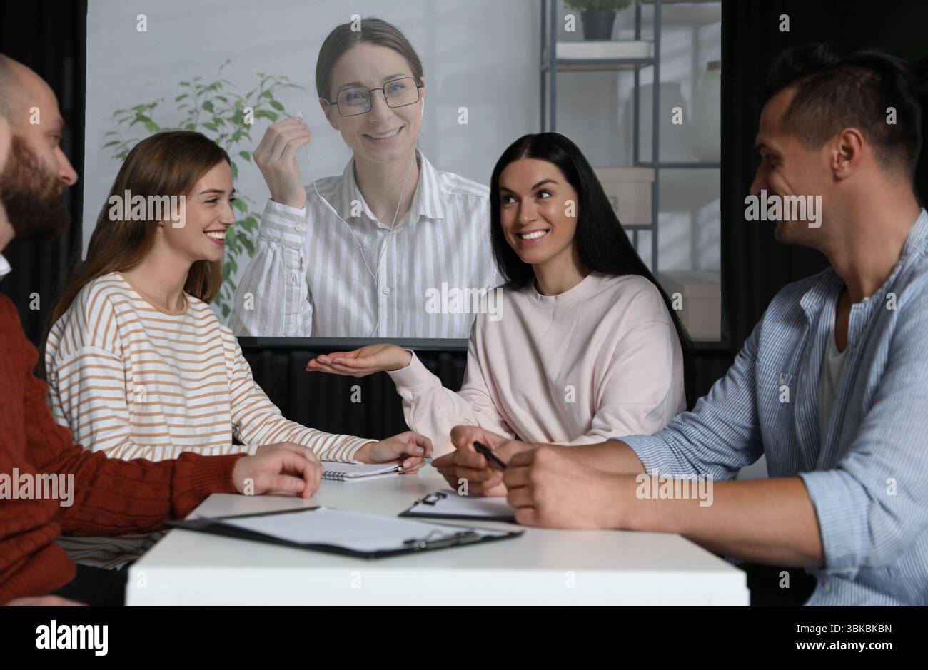 Gruppo di persone che partecipano a una conferenza aziendale al chiuso. Altoparlante sullo schermo di proiezione Foto Stock