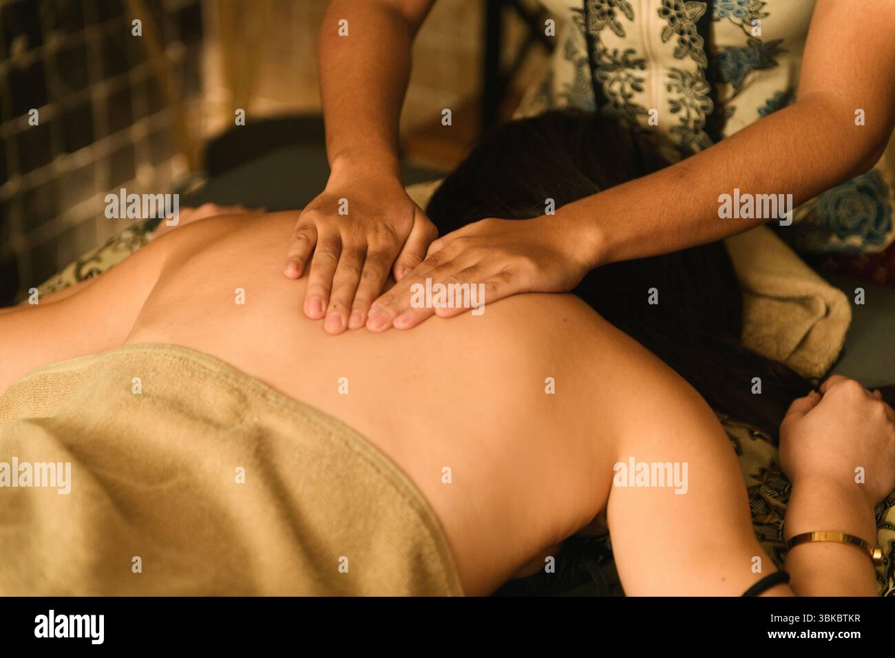 Massaggiatore professionista che offre agli ospiti un trattamento rilassante alla schiena nell'elegante ambiente spa dell'hotel. Foto Stock