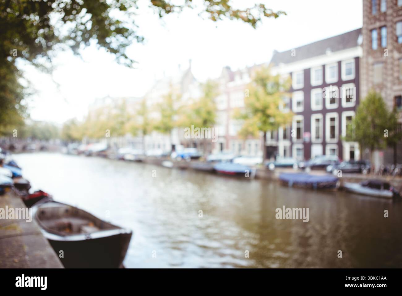 La piccola barca a remi galleggia sul bordo di pietra in un canale dal design piatto con barche ormeggiate e case in mattoni Foto Stock