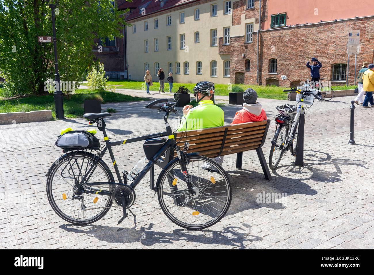 Ciclisti che si rilassano sulla panchina, Świętego Ducha, città vecchia, Danzica, voivodato della Pomerania, Repubblica di Polonia Foto Stock
