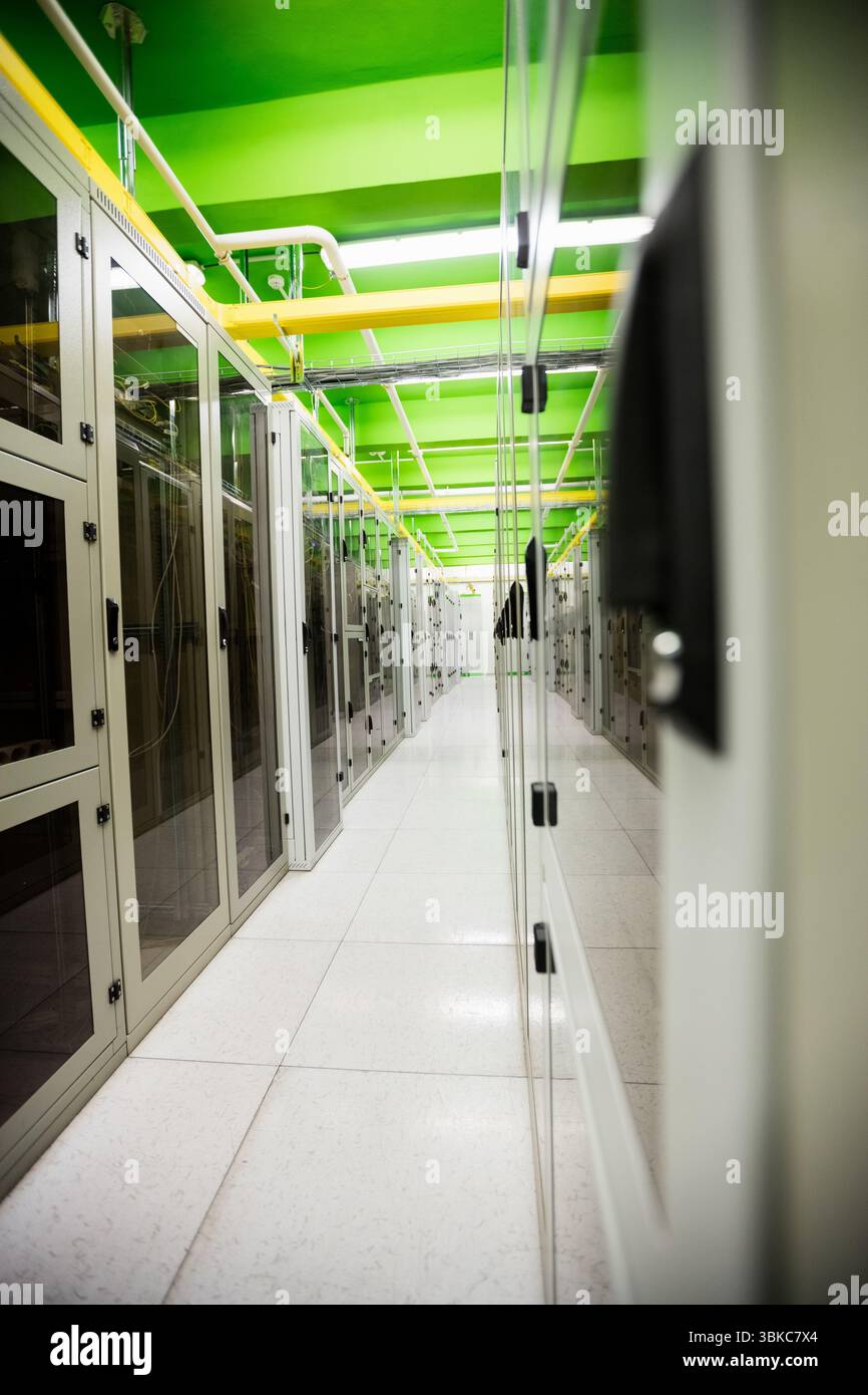 Il corridoio della sala server dal design piatto viene mostrato con pavimento bianco, cavi di rete e travi verdi Foto Stock