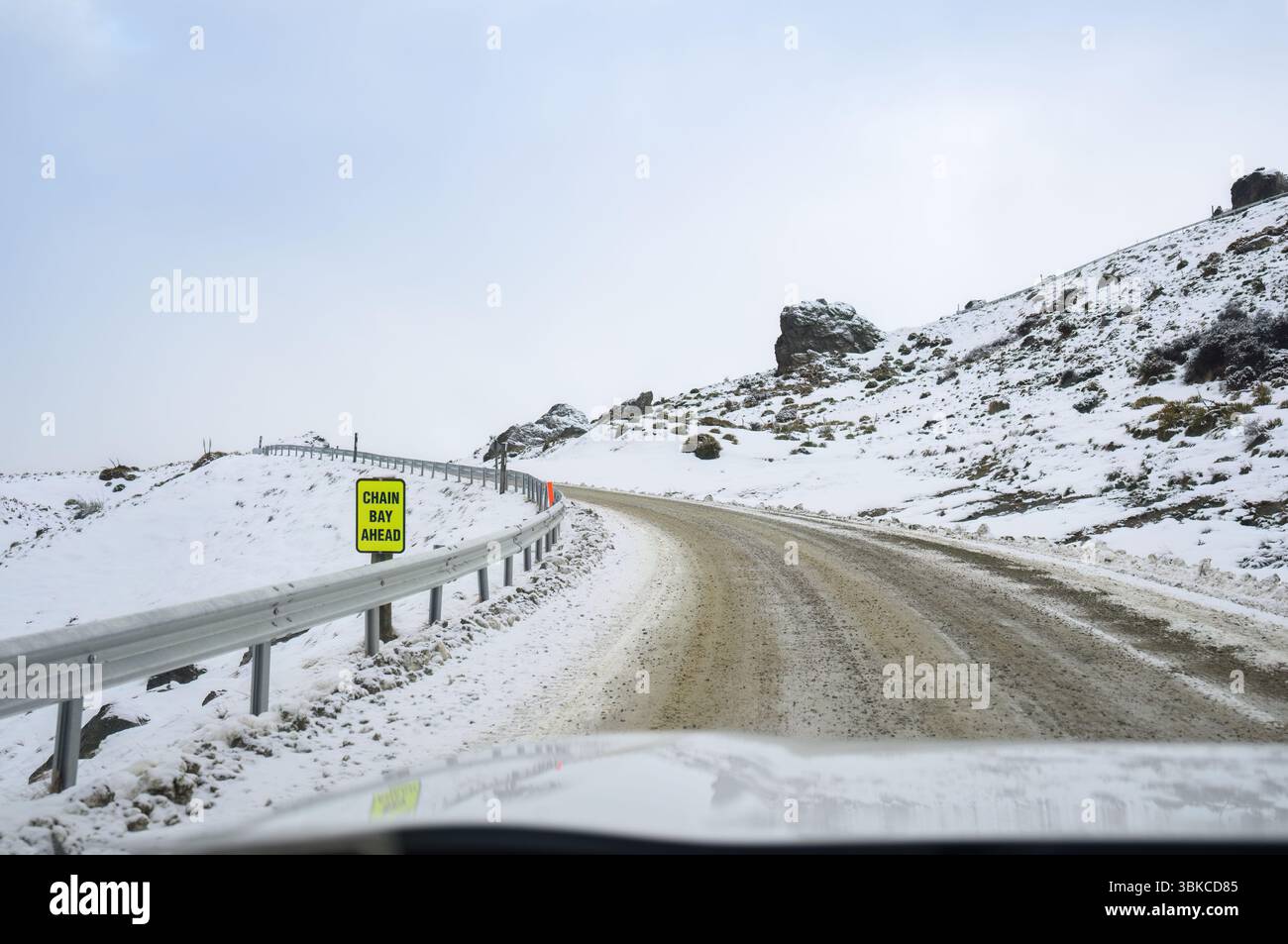 Cartello stradale DI CHAIN BAY DAVANTI a una strada di montagna ghiacciata. Wanaka. Regione di Otago. Isola del Sud. Foto Stock
