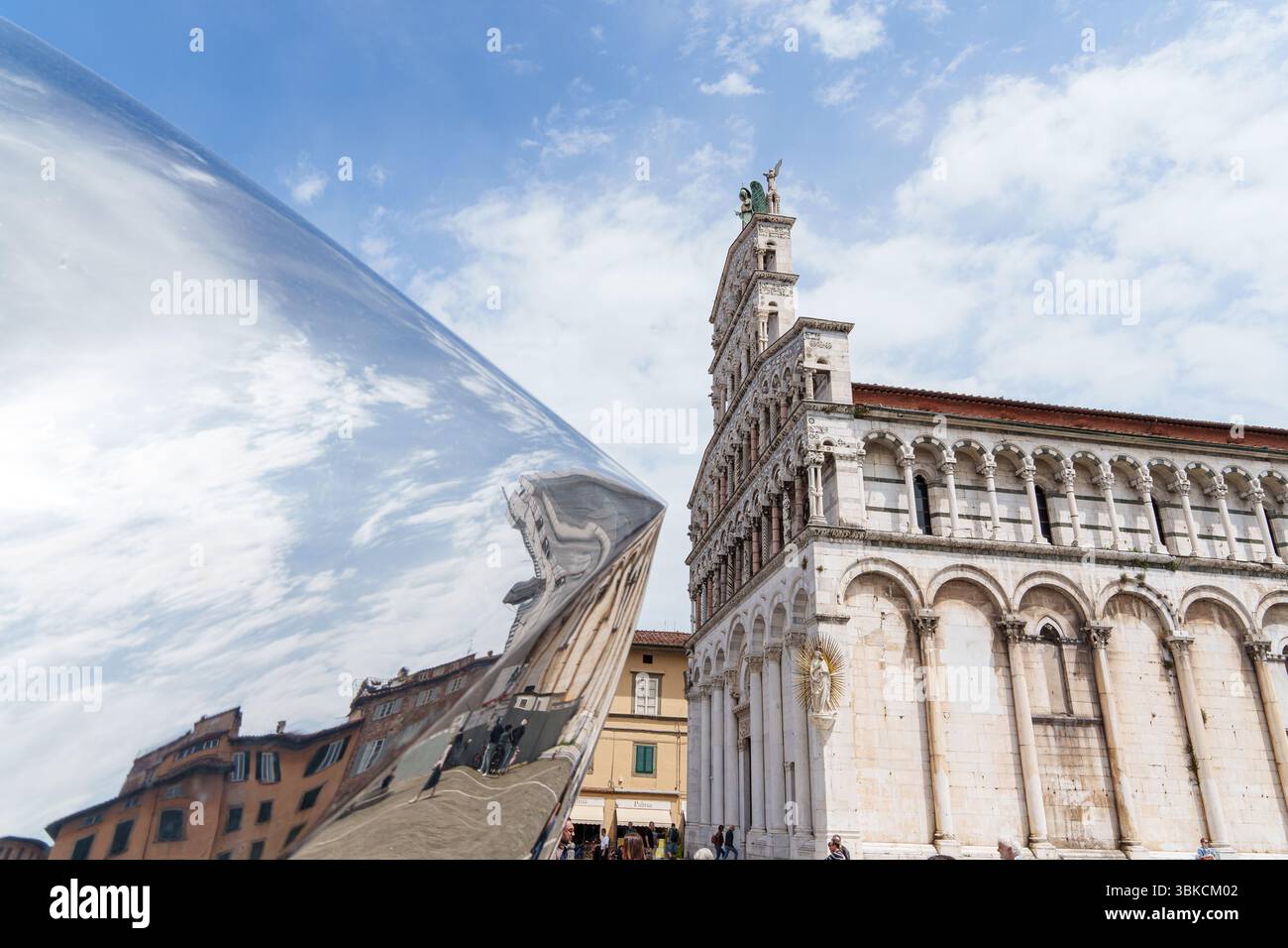 Facciata della chiesa di San Michele in foro a Lucca, Italia, con archi ornati e statue sotto il cielo nuvoloso. Foto di alta qualità Foto Stock