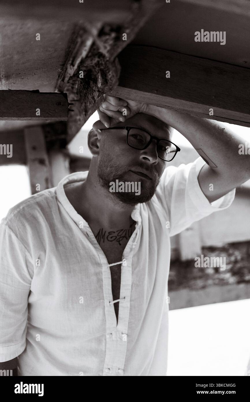 Uomo in vetro appoggiato sotto una struttura rustica in legno Foto Stock