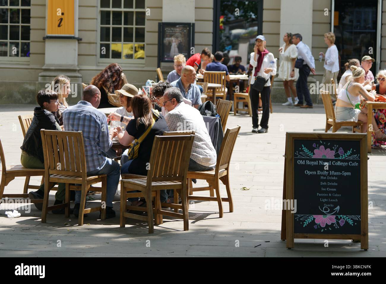 La gente ama cenare all'aperto in un caffè locale in una giornata intensa e soleggiata. Greenwich, Londra, Inghilterra Foto Stock