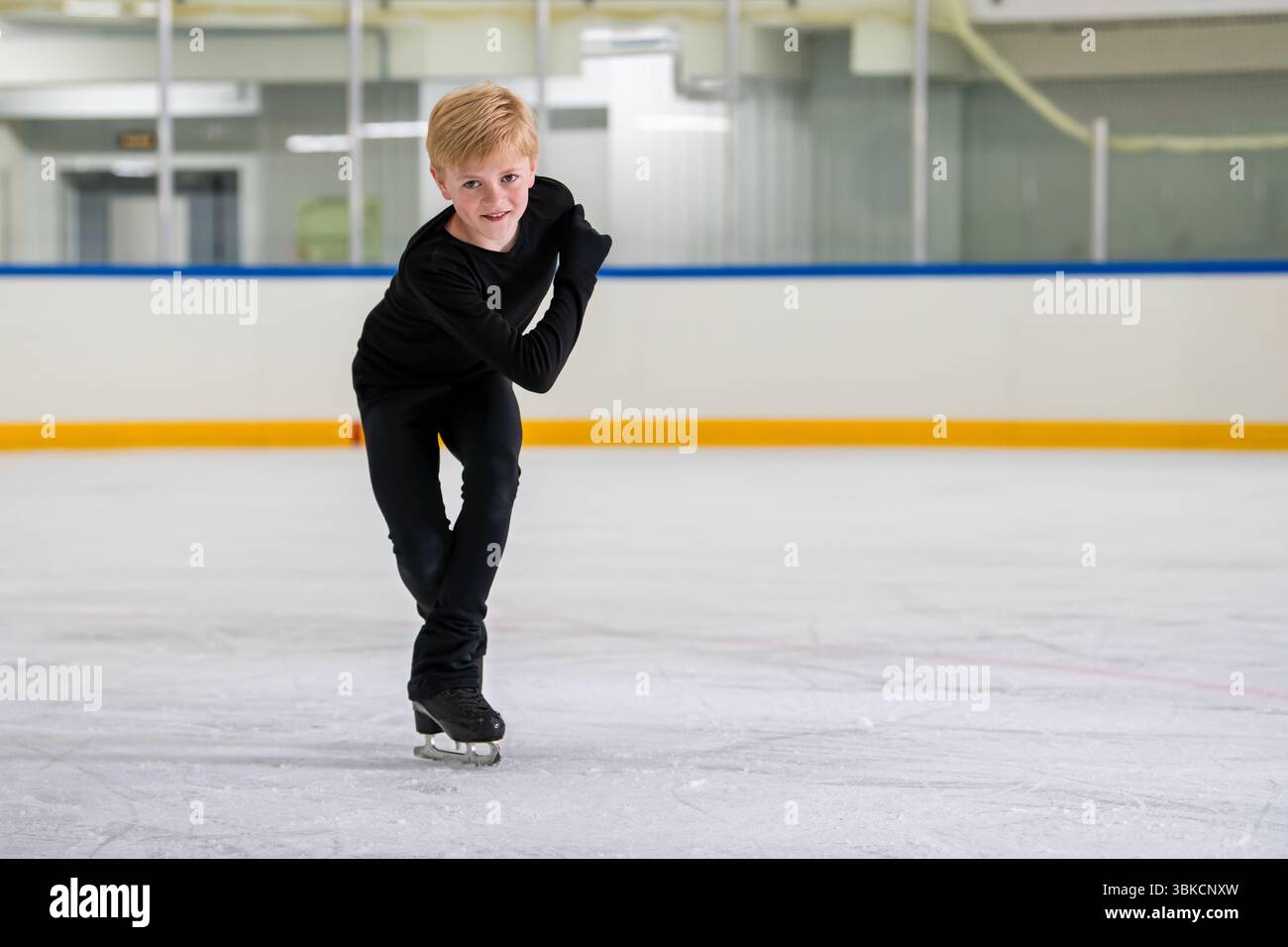 il bambino pattina su una pista coperta Foto Stock