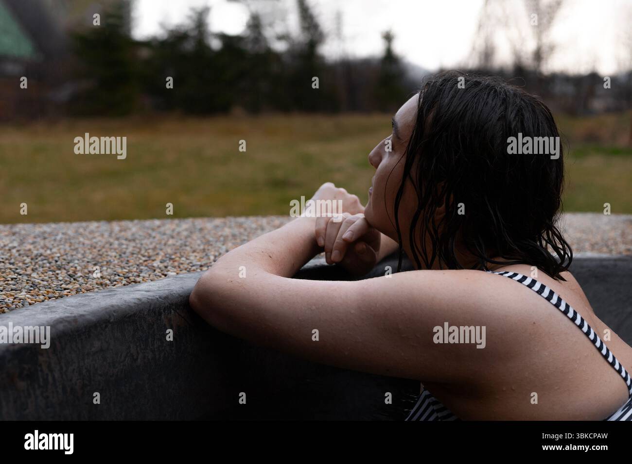 una giovane donna siede tranquillamente in un bagno caldo, abbracciato dal calore e dalla calma. Foto Stock