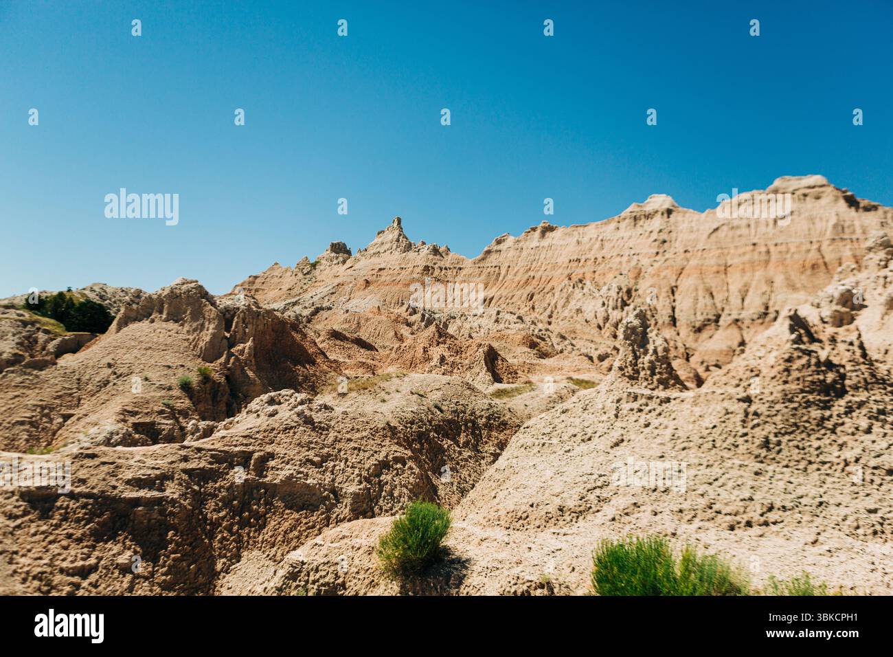 Creste rocciose illuminate dal sole e pendii sotto il cielo azzurro delle Badlands Foto Stock