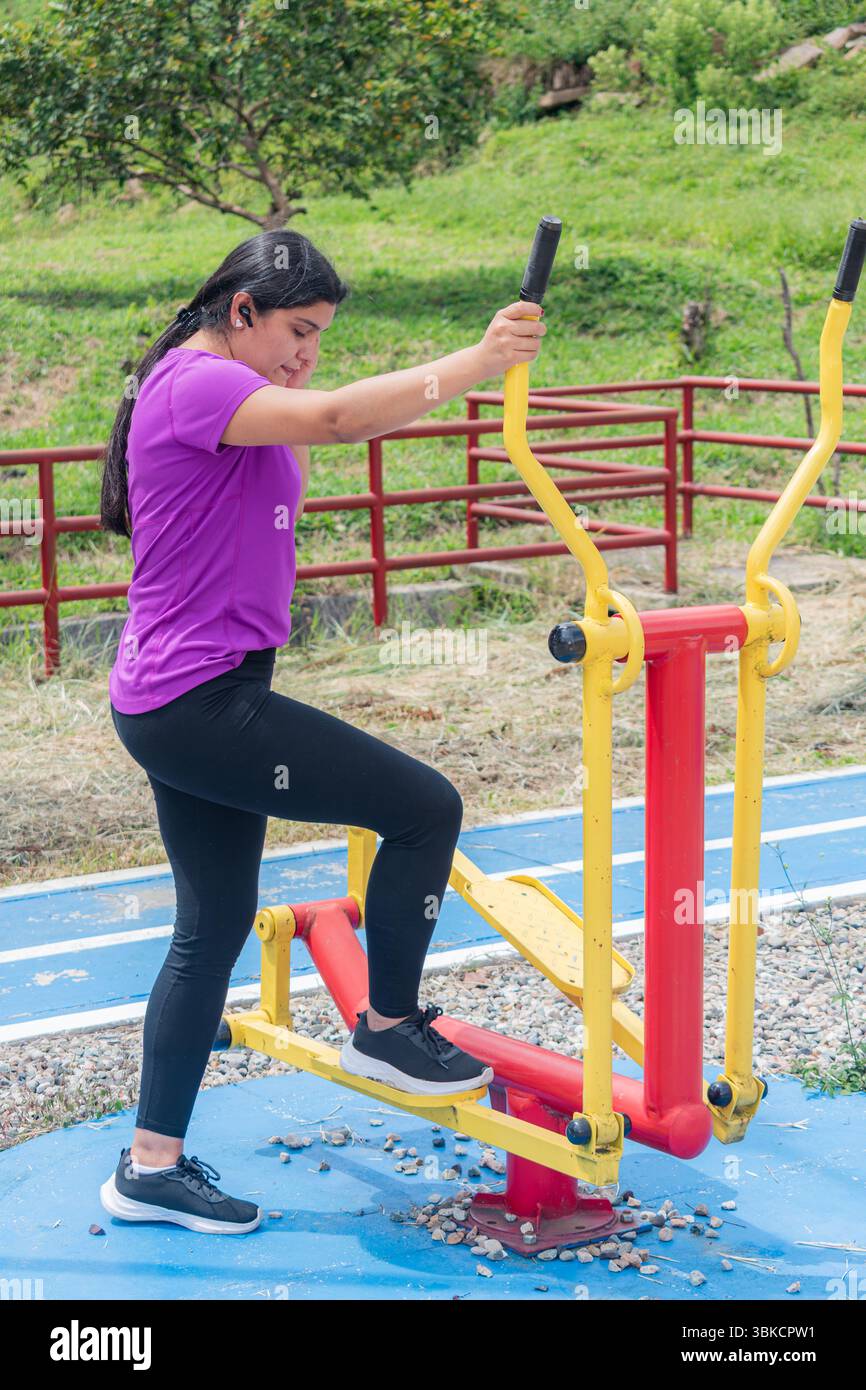 Donna latina che si prepara a utilizzare l'ellittica per esterni Foto Stock