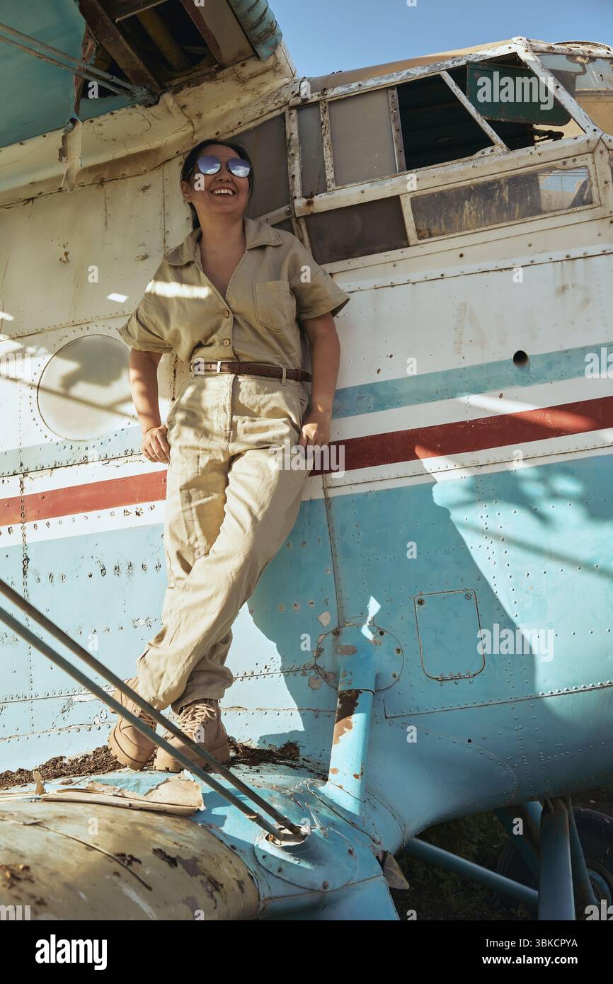Donna in tuta di volo in aereo, sorridente Foto Stock