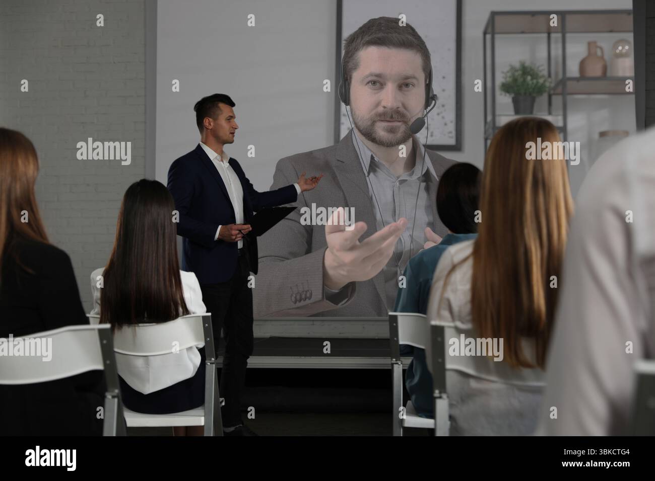 Gruppo di persone che partecipano a una conferenza aziendale al chiuso. Altoparlante sullo schermo di proiezione Foto Stock