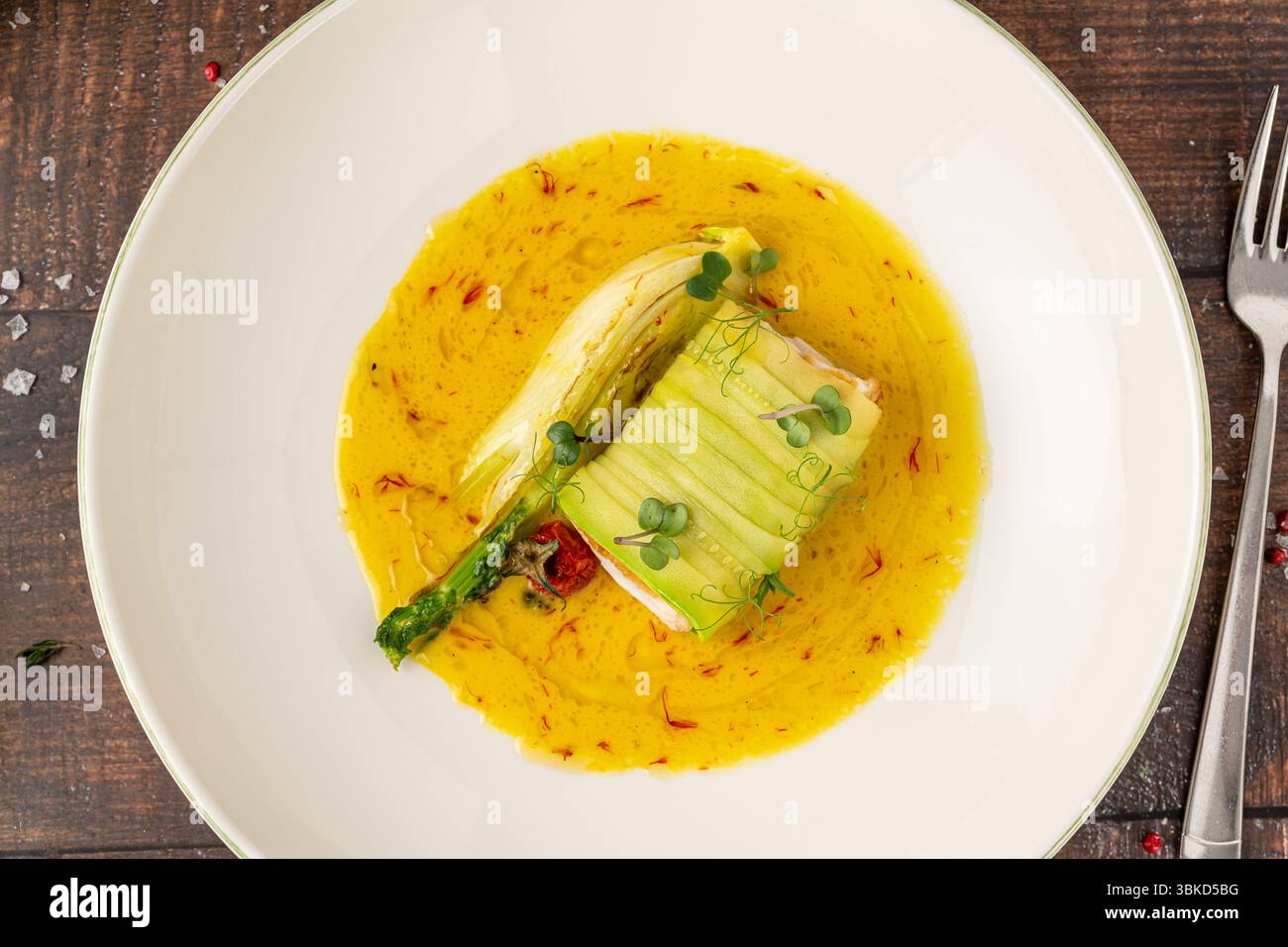 Filetto di pesce ricoperto di zucchine in salsa gialla allo zafferano Foto Stock