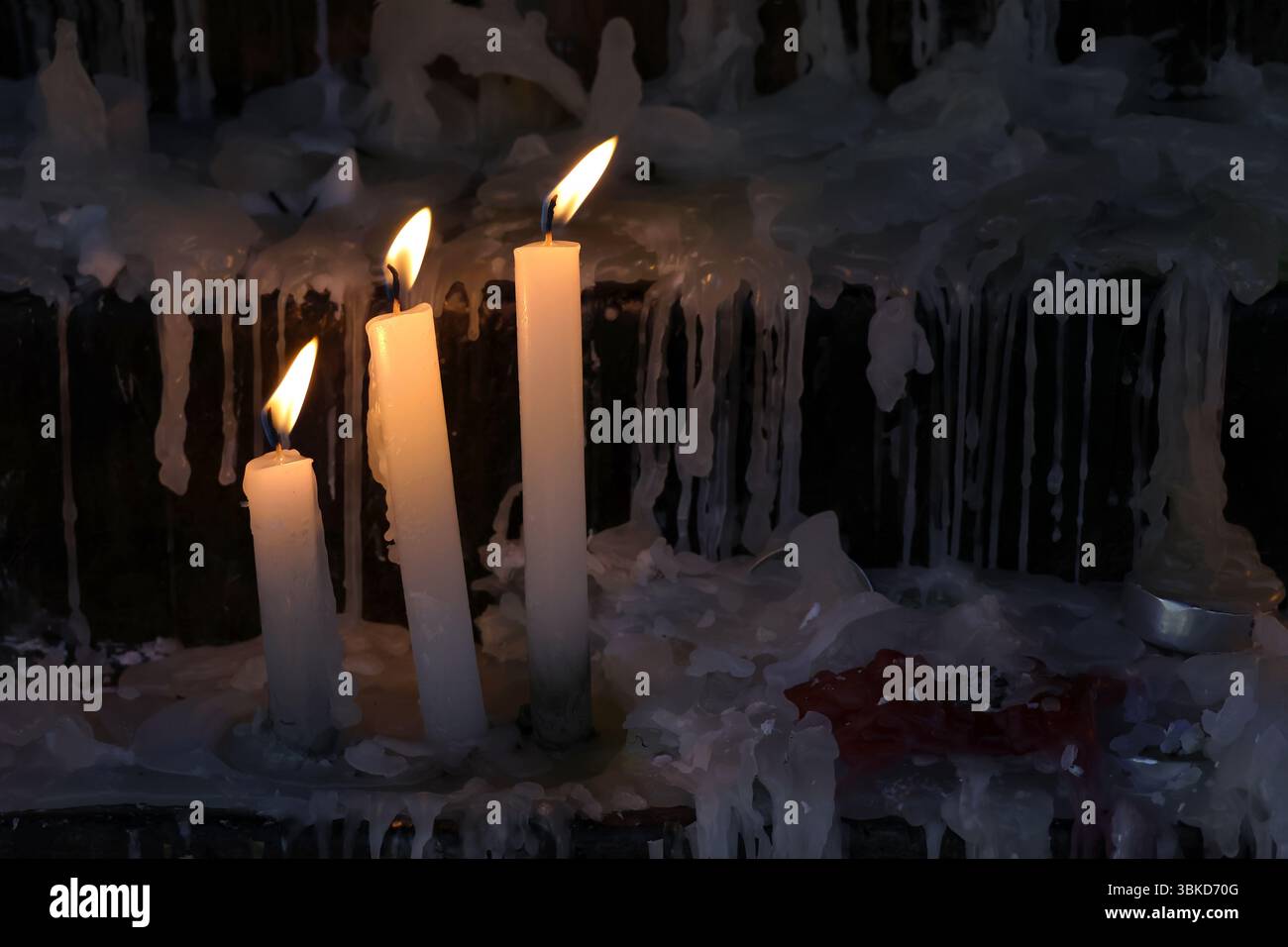 Tre candele accese in un ambiente di culto cristiano tranquillo e riverente. Il lume di candela simboleggia la fede, la preghiera e la presenza di Dio. Ideale per Foto Stock