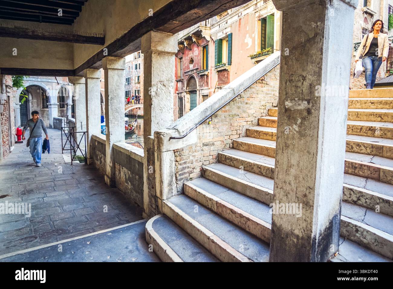 Angolo tranquillo di Venezia con scale, colonne e un ponte sul canale, fuori dal percorso turistico, che rivela il fascino nascosto della città ogni giorno. Foto Stock