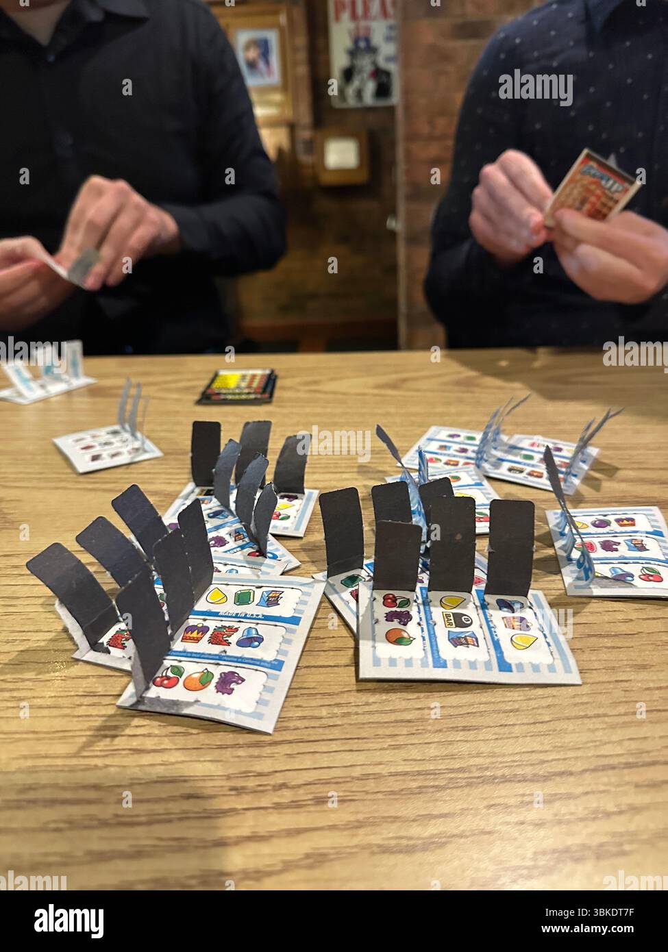 Primo piano tra le mani di due persone che tirano i biglietti per il gioco d'azzardo in un bar del Minnesota. Foto Stock