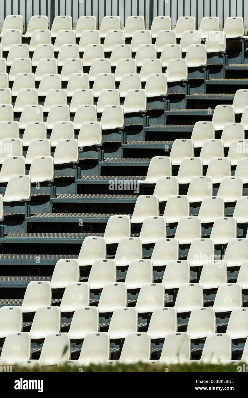 Posti vuoti bianchi disposti in fila attendono gli spettatori in uno stadio. Foto Stock