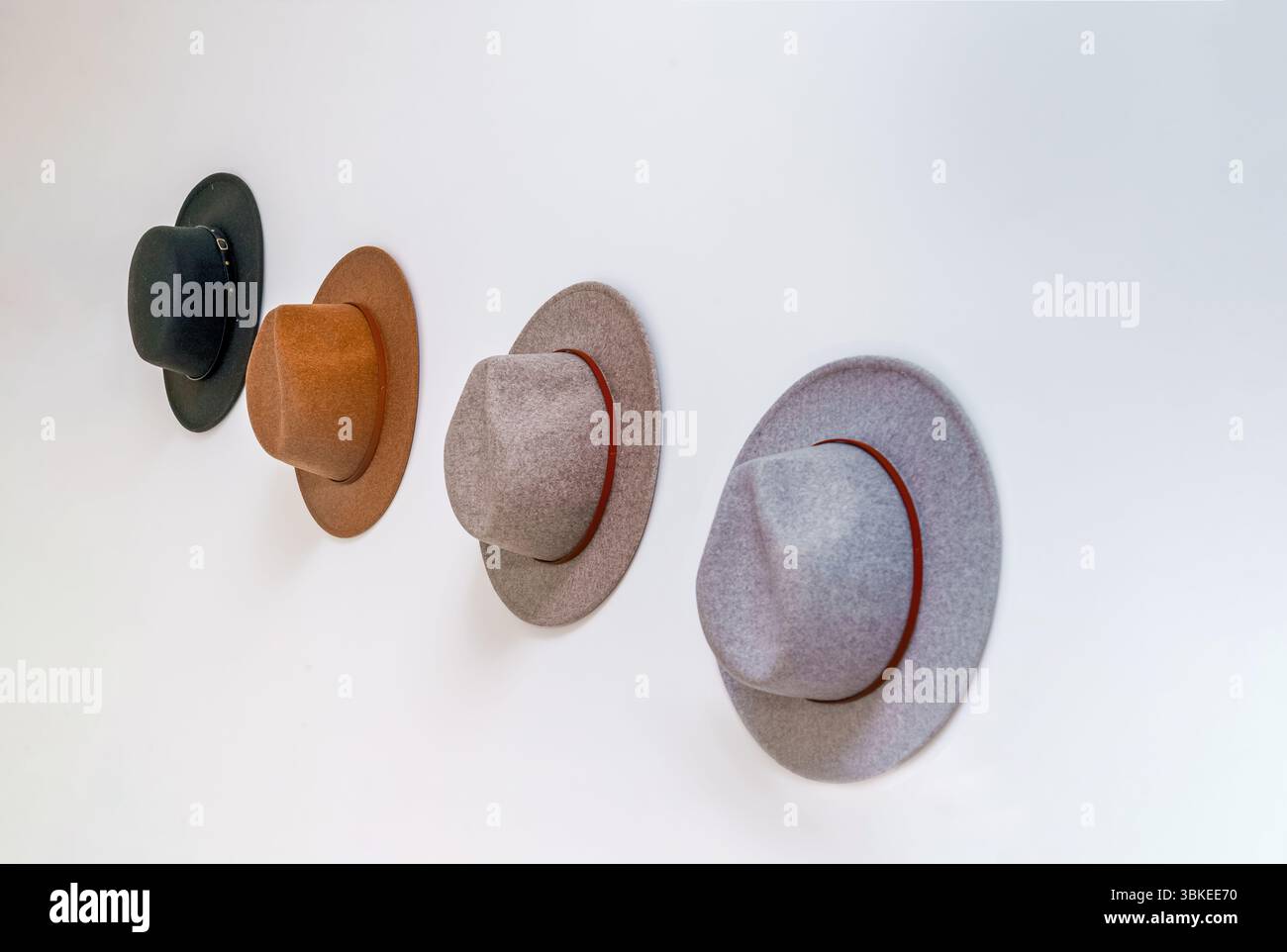 Cappelli western in feltro da cowboy nero marrone grigio su parete bianca angolati con spazio per copie. Con molti cappelli. Foto Stock