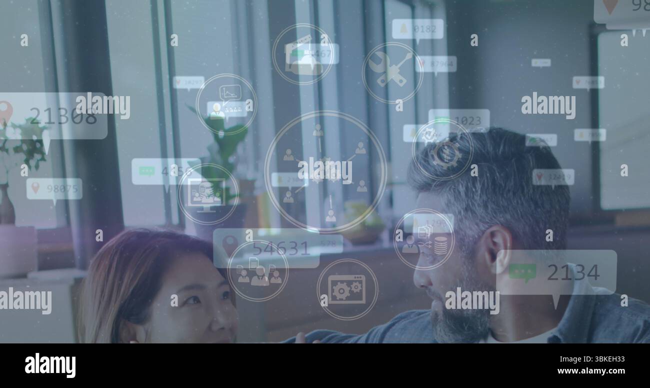 Discutere di colleghi vestiti casualmente scambiando idee in ufficio, con notebook, piante e icone Foto Stock