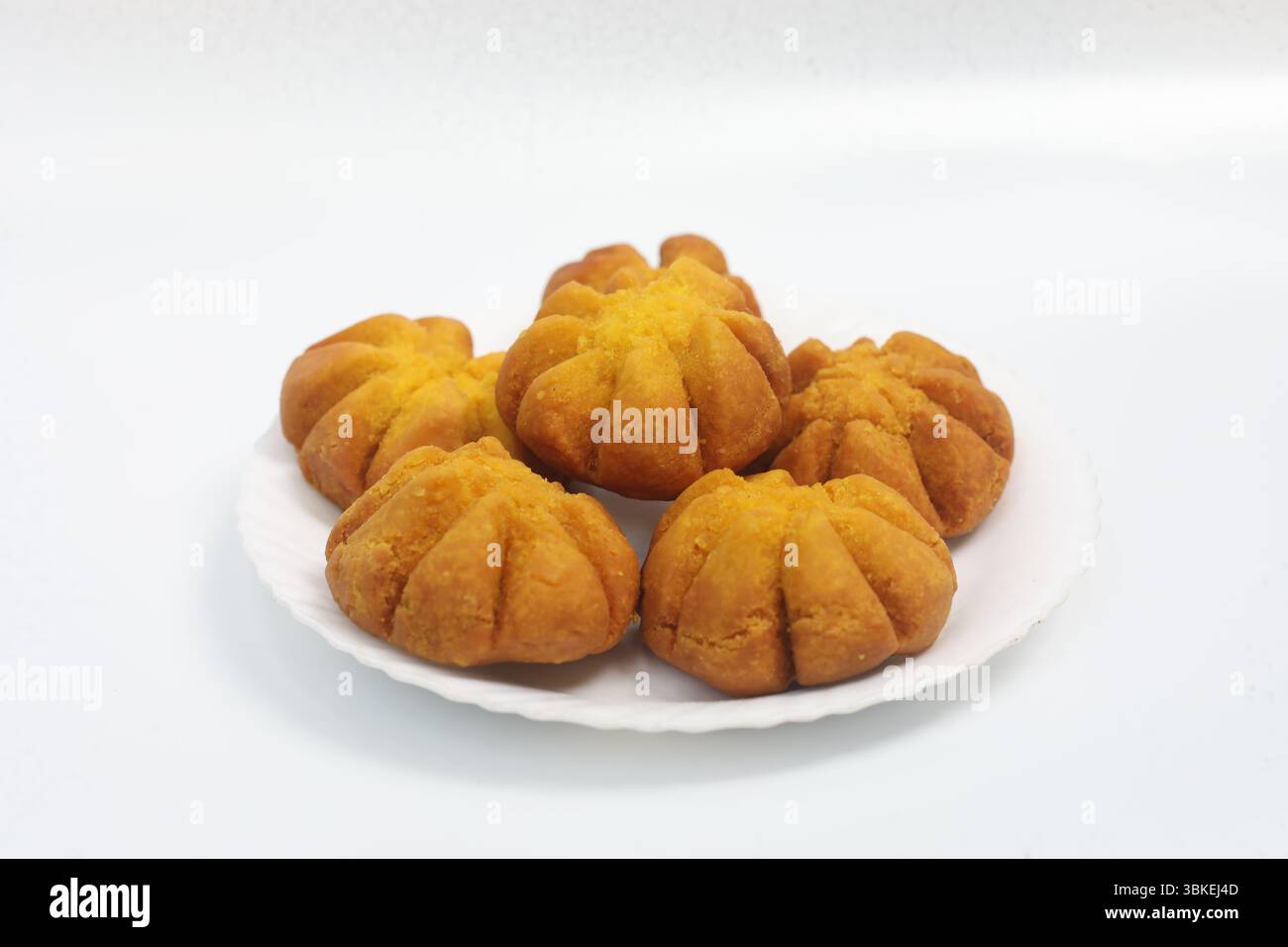 Tradizionale spuntino dolce dell'India meridionale a forma di fiore, fritto in profondità alla perfezione e servito su un piatto bianco. Croccante, festoso e delizioso. Foto Stock