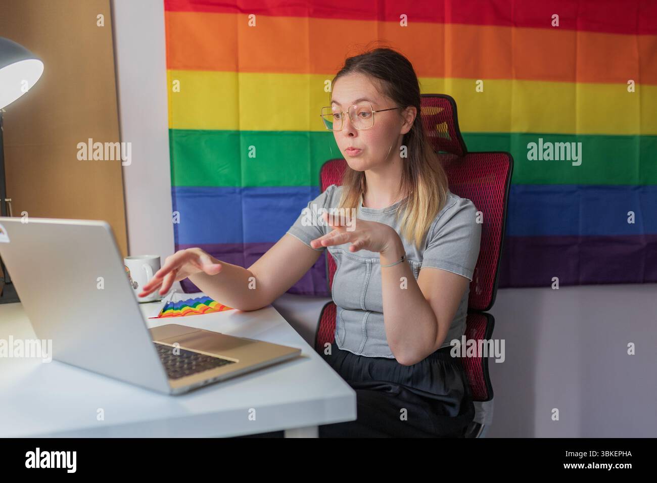 La giovane donna parla in modo esplicito durante una sessione di lavoro a distanza con orgoglio. Una lavoratrice di sesso medio si inclina verso un notebook, comunicando con vivi Foto Stock