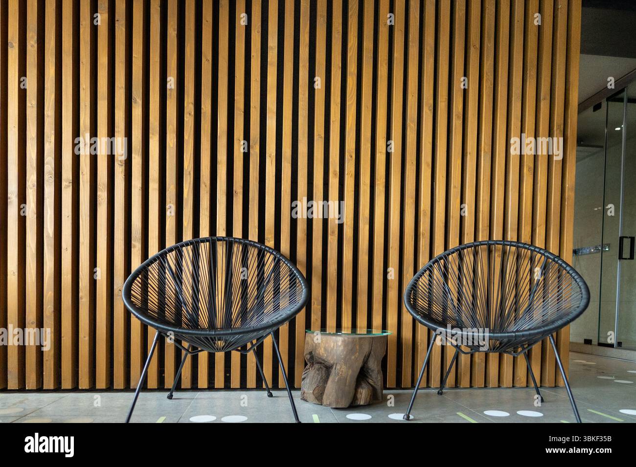 Due sedie in piedi l'una accanto all'altra in una spa sullo sfondo di spranghe di legno. Foto Stock