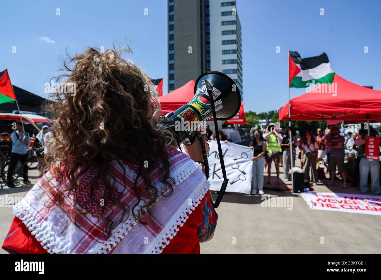 Bonn, Germania, Germania. 19 giugno 2025. Un manifestante si rivolge a una folla di corno al di fuori del World Conference Center di Bonn durante i colloqui sul clima SB62, amplificando gli appelli alla sovranità indigena e alla solidarietà palestinese. La bandiera "Land Back” e le bandiere alzate evidenziano l'intersezione tra giustizia climatica, decolonizzazione e diritti umani al centro della protesta. (Credit Image: © Bianca Otero/ZUMA Press Wire) SOLO PER USO EDITORIALE! Non per USO commerciale! Foto Stock