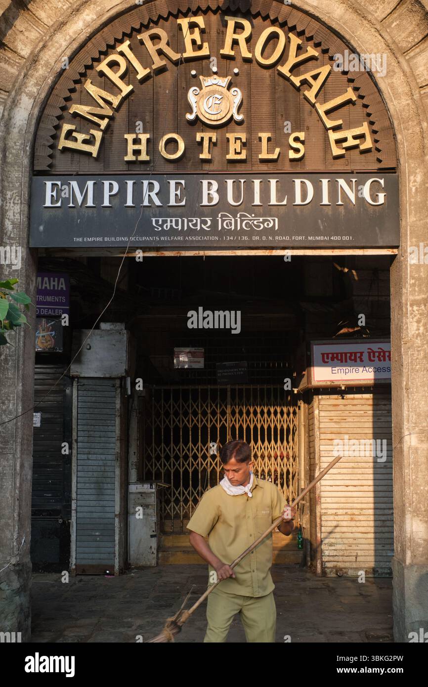 Un pulitore municipale spazza la strada fuori dal defunto Empire Royale Hotel, Empire Bldg., Dr. Dadabhai Naoroji Rd., zona di Fort, Mumbai, India Foto Stock