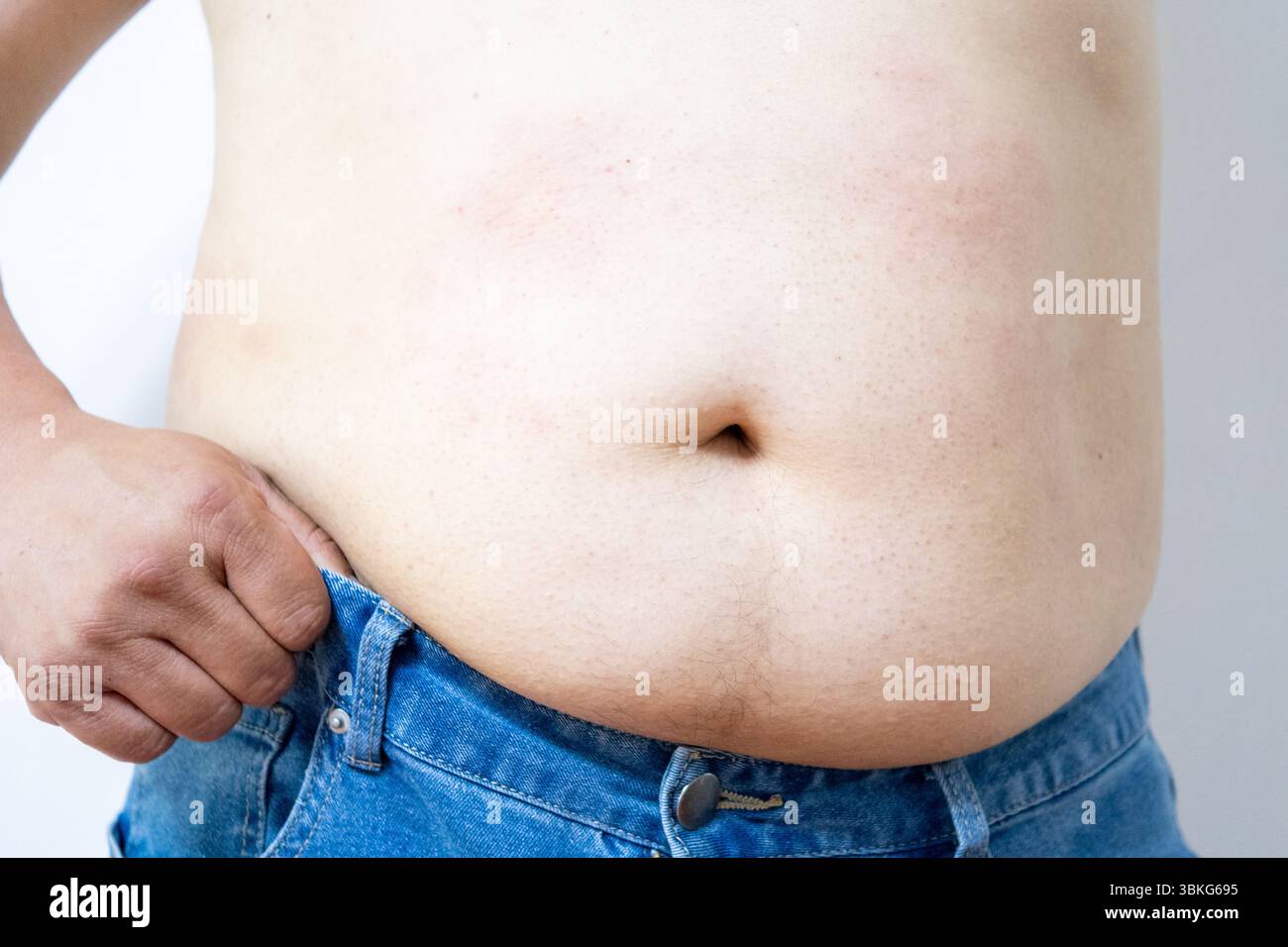 Corpo uomo obesità, pancia maschile grasso, primo piano su sfondo bianco.evidenziando problemi di obesità o peso corporeo. Foto Stock