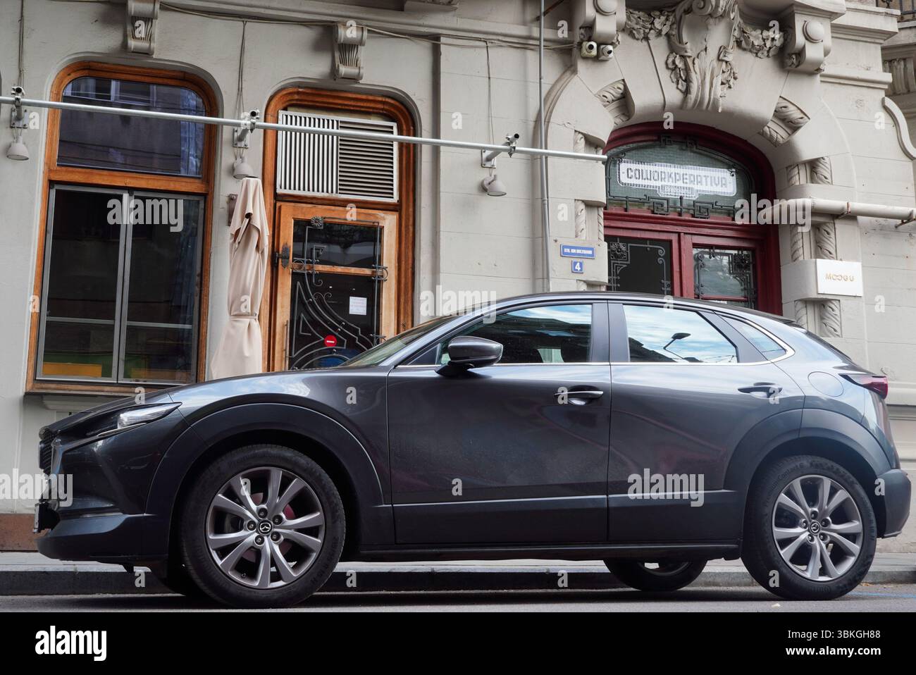 Bucarest, Romania – 20 giugno 2025: Vista ravvicinata della Mazda CX 30 auto grigia parcheggiata sulla strada di fronte al pub Foto Stock