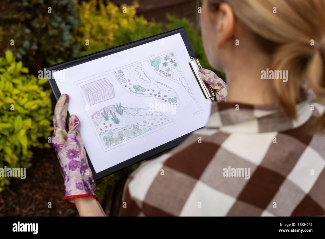 design paesaggistico. donna giardiniere che guarda la piantina del giardino di casa Foto Stock