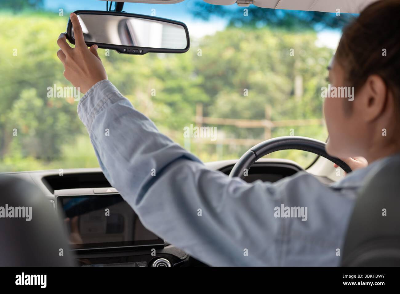 donna regola lo specchietto retrovisore dell'auto prima della guida, guida con intento, guida sicura, pratica di guida, donna allegra seduto comodamente sul sedile del conducente wi Foto Stock