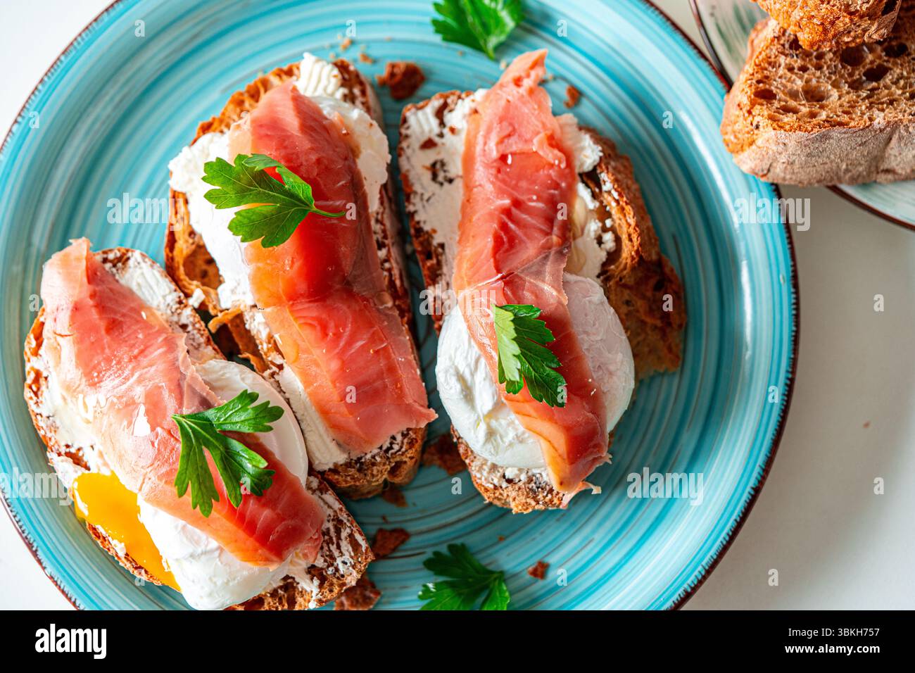 Tostare con uova in camicia, formaggio spalmabile e pesce rosso su un piatto blu. Colazione deliziosa e salutare. Vista dall'alto. Foto di alta qualità Foto Stock