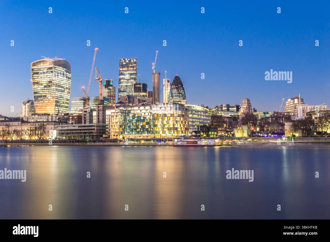 Il moderno skyline di Londra maestosamente illuminato al tramonto con la splendida riflessione sul fiume Foto Stock