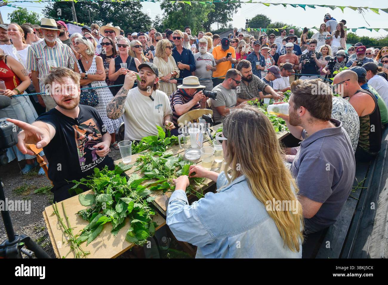 Marshwood, Dorset, Regno Unito. 21 giugno 2025. Meteo nel Regno Unito. I concorrenti guardati da una grande folla entusiasta prendono parte ai Campionati mondiali annuali di alimentazione dell'ortica che sono tornati nella loro casa spirituale al Bottle Inn di Marshwood nel Dorset dopo sei anni di distanza dopo la ristrutturazione e la riapertura dello storico pub. Lo scopo del concorso è quello di mangiare le foglie dal maggior numero possibile di due gambi di ortica in un'ora che viene lavata via da una bevanda alcolica o acqua. I vincitori sono stati Michael Hobbs, 44 anni, e Lucy Dermondy, 22 anni. Crediti fotografici: Graham Hunt/Alamy Live News Foto Stock