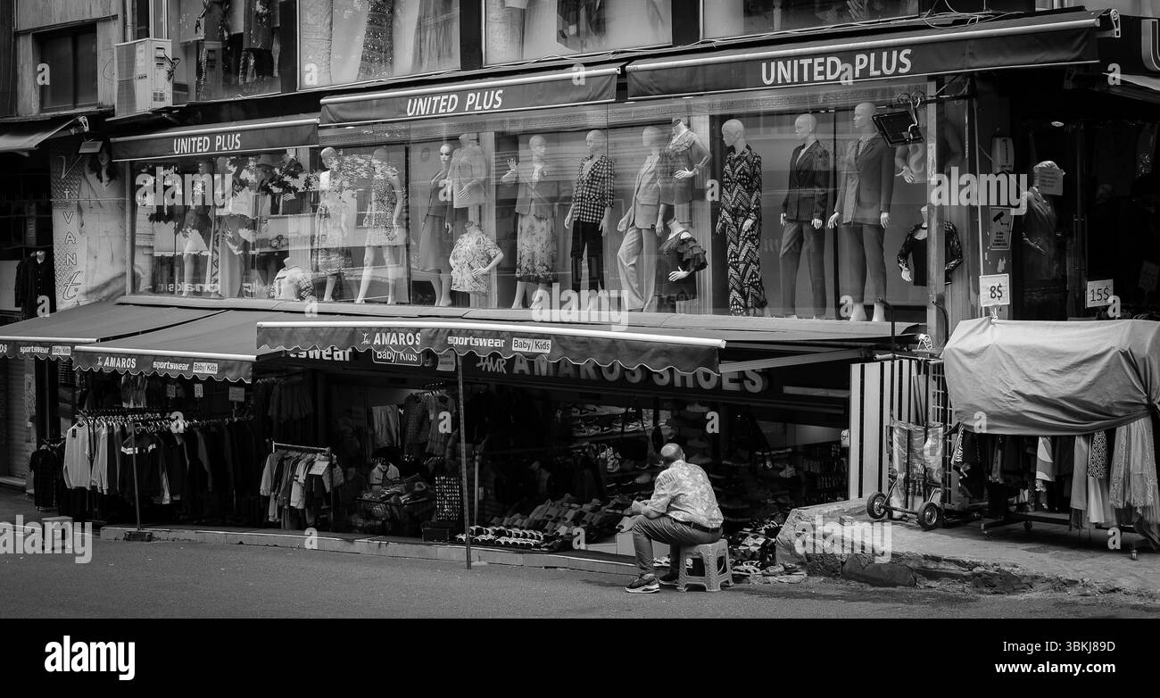 Gli amanti dello shopping passeranno accanto a un vivace negozio di abbigliamento a Istanbul, con manichini vestiti con abiti eleganti. Un uomo si siede tranquillamente nelle vicinanze, osservando. Foto Stock