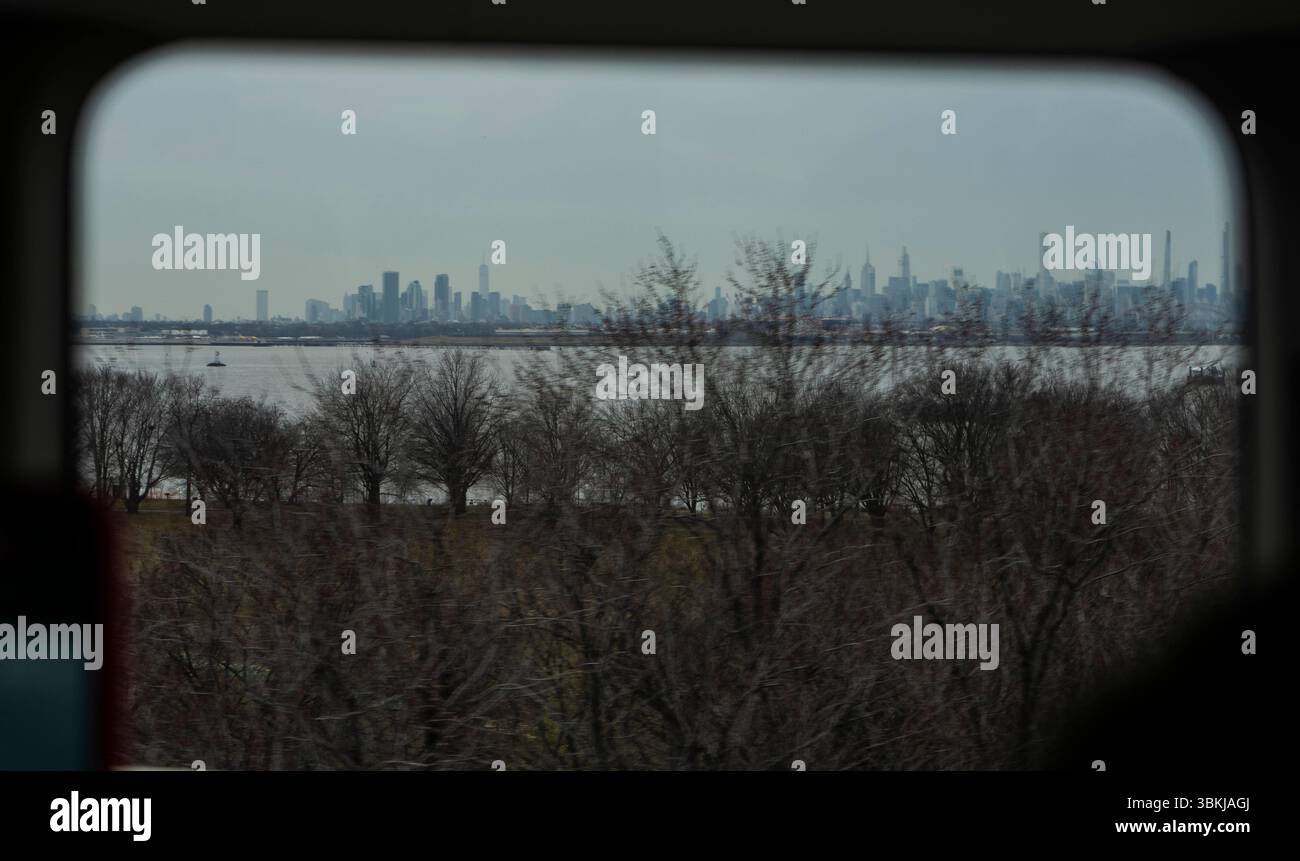 Uno skyline della città visto attraverso una finestra con alberi in primo piano, probabilmente preso in una giornata cupa. La scena cattura un contrasto tra natura e UR Foto Stock