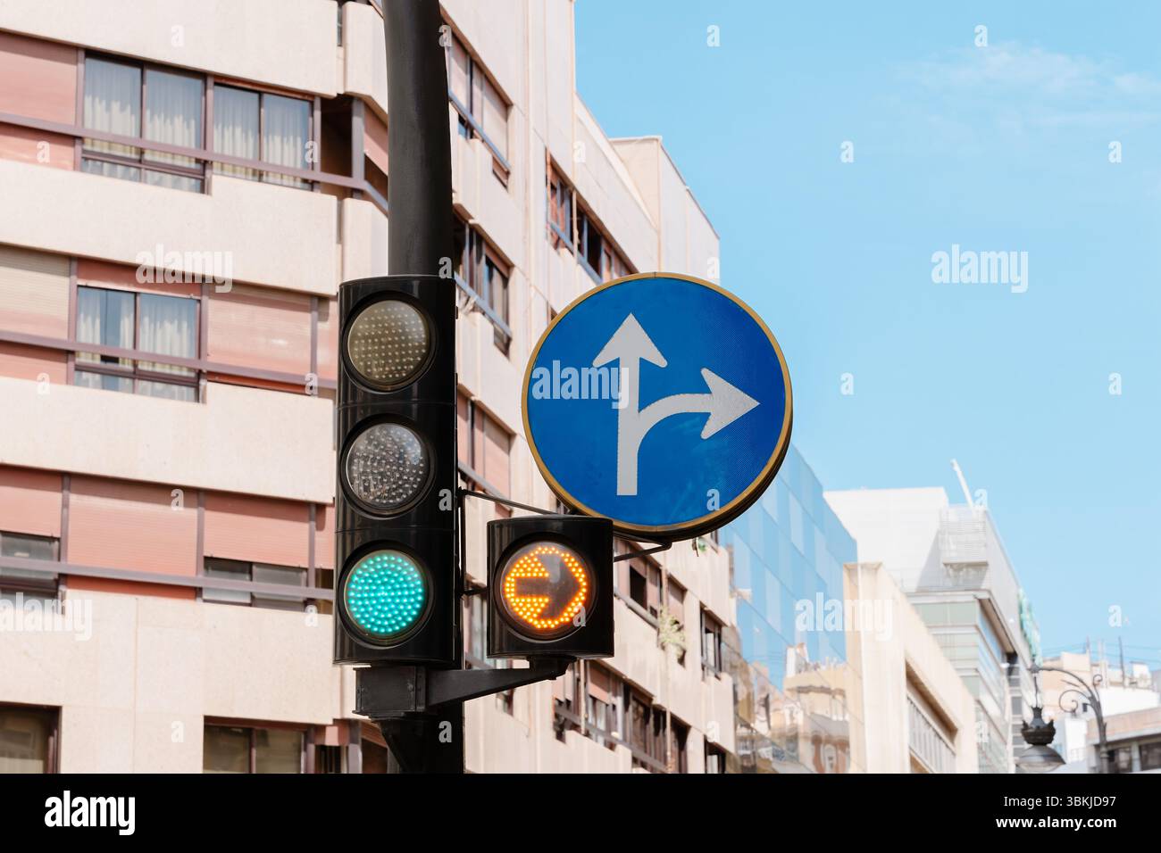 Vista sulla strada urbana con semaforo verde e cartello blu che mostra solo le svolte a destra e in avanti. Pianificazione urbana, sistema di trasporto Foto Stock