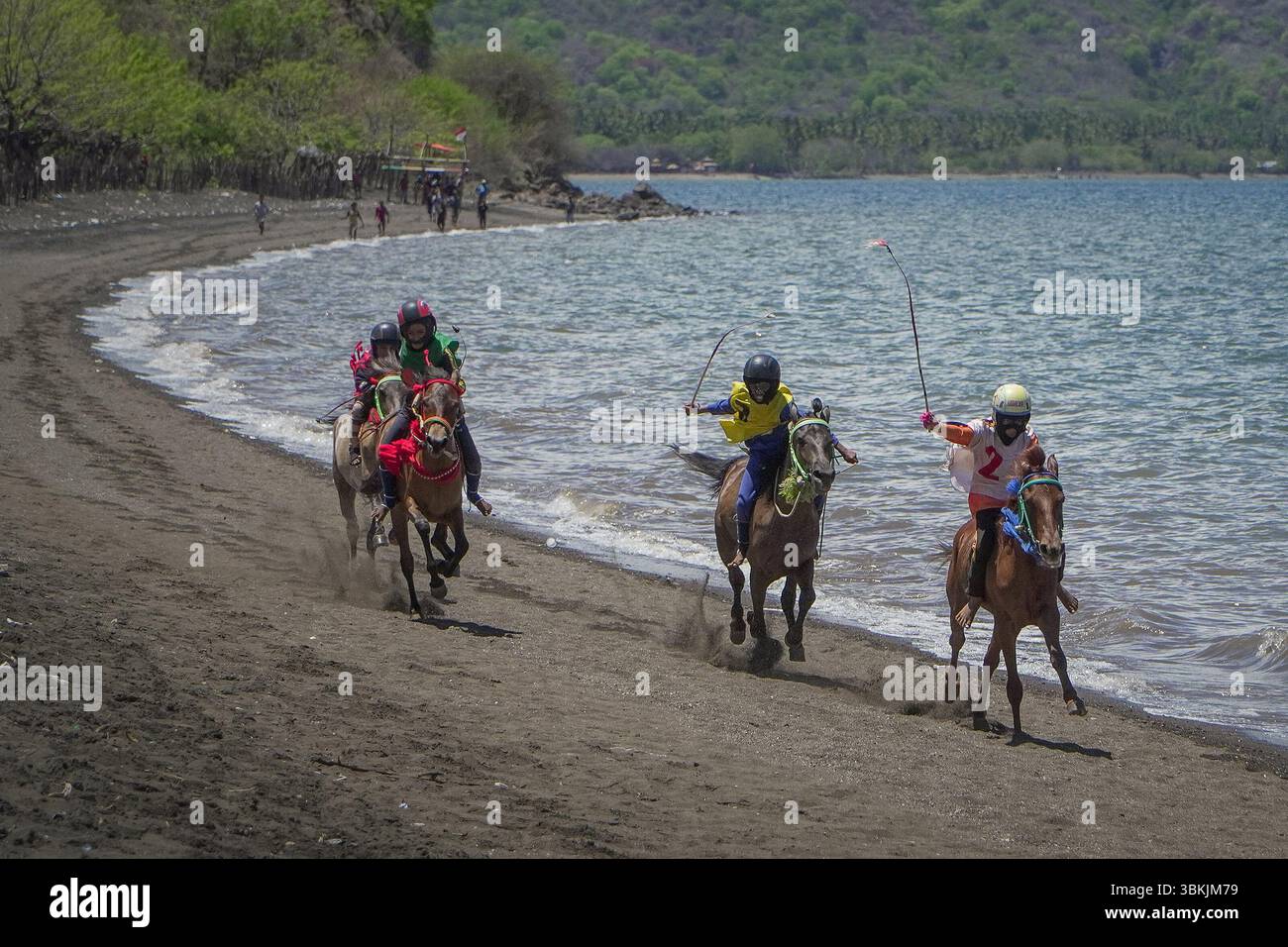 BIMA, 23 novembre 2021: I fantini corrono a cavallo lungo una spiaggia panoramica, navigando sapientemente la costa con colori vivaci e vivaci competizioni Foto Stock