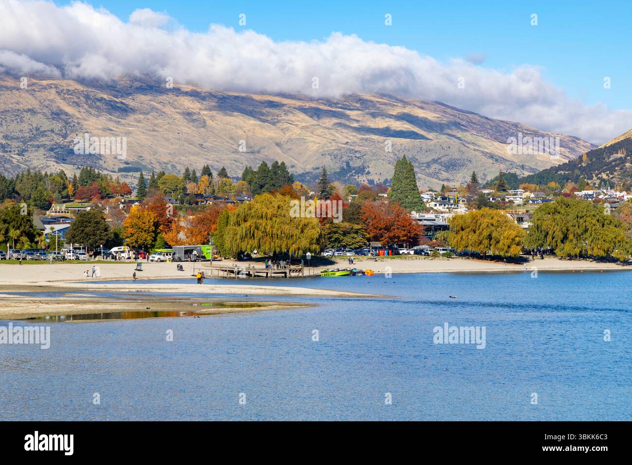 La spiaggia di Wanaka e il lago Wanaka in una giornata d'autunno soleggiata, vista di Roys Bay verso il centro della città, Otago, South Island, nuova Zelanda Foto Stock