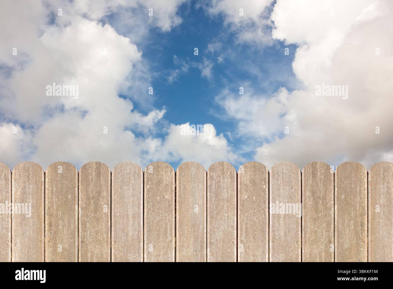 La recinzione in legno si estende lungo il fondo sotto un cielo parzialmente nuvoloso, con un aspetto resistente agli agenti atmosferici in un design piatto Foto Stock