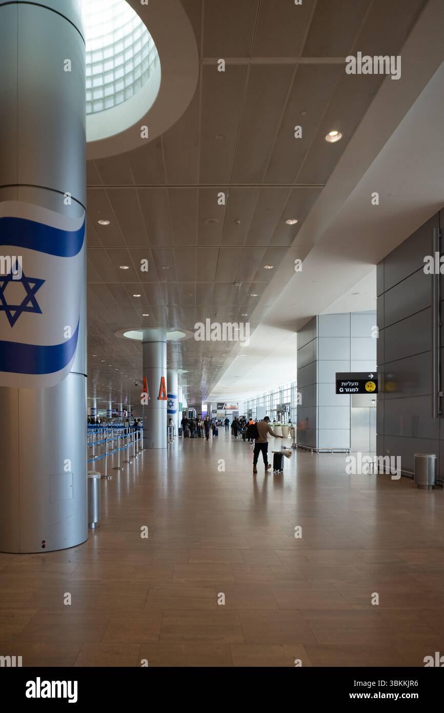 I viaggiatori passano attraverso un terminal dell'aeroporto Ben Gurion quasi vuoto tra le cancellazioni di volo diffuse a causa della guerra Foto Stock