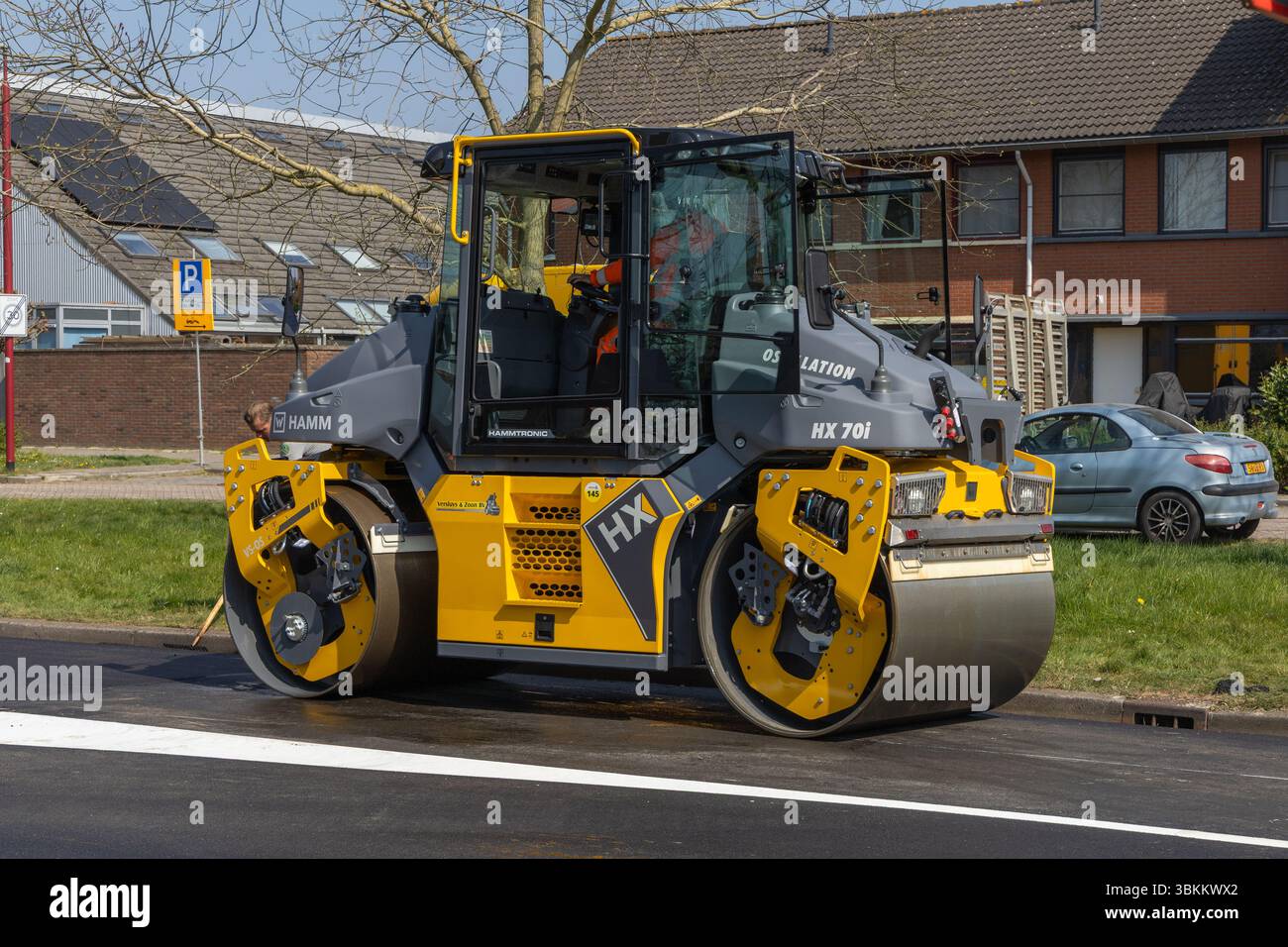 I moderni rulli tandem compattano asfalto fresco nelle giornate di sole, mostrando i macchinari per la costruzione di strade in azione in una strada periferica. Utrecht, Nethe Foto Stock
