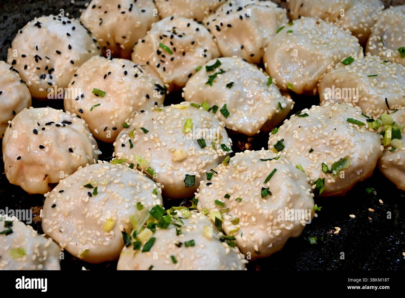 Shengjian è deliziosa specialità di Shanghai, il pan-ciambelle fritte riempite con carne e succhi di frutta. Foto Stock