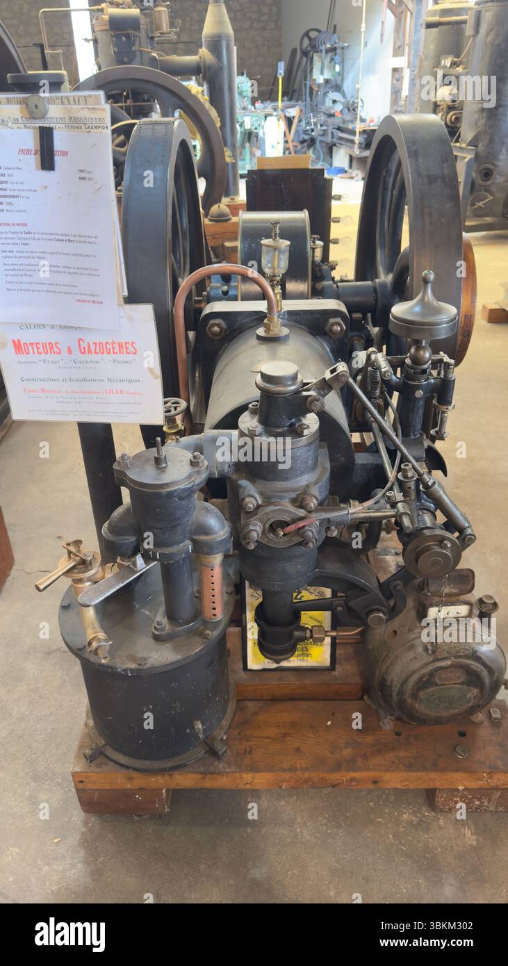 Vista frontale di un motore a combustione interna vintage nero su una base in legno in un ambiente industriale. Foto Stock