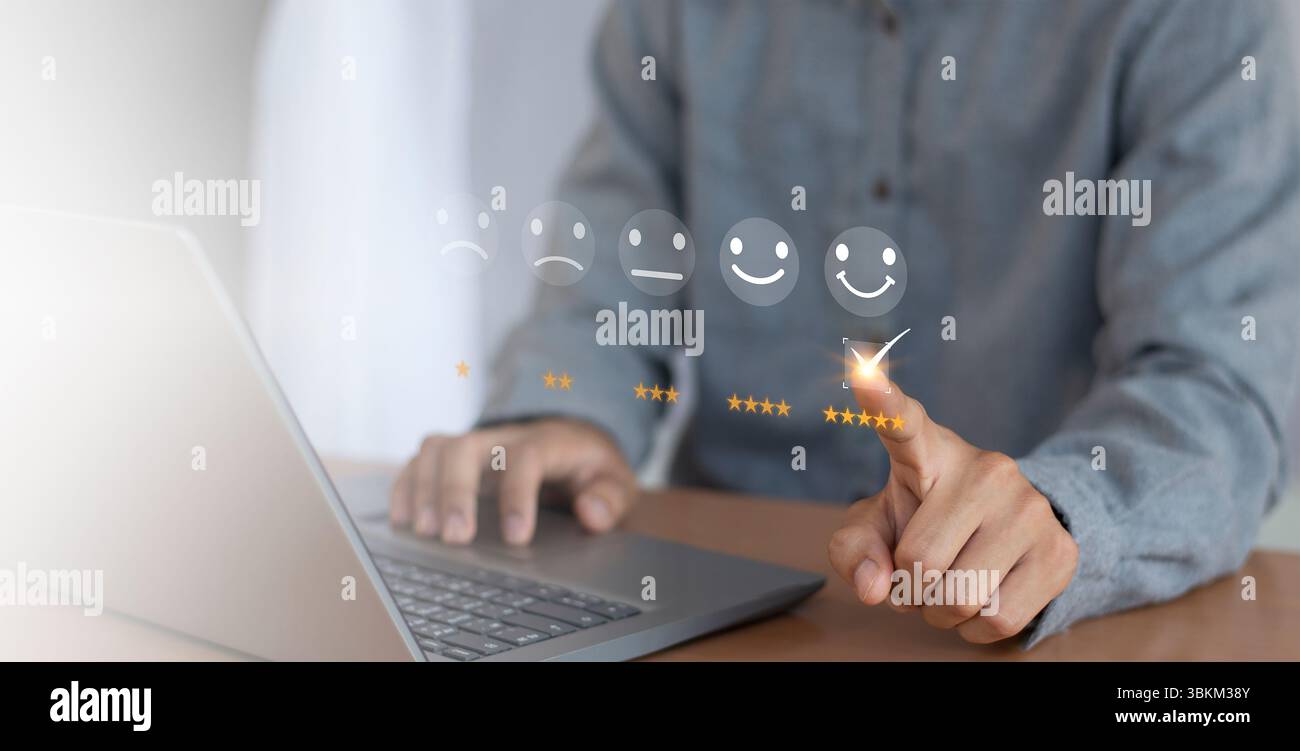 Valutazione del servizio clienti e concetto di feedback. Uomo d'affari che utilizza un computer portatile con l'icona della faccia sorridente. Foto Stock